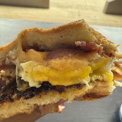 Kapwa Coffee Bar - Pandesal breakfast sandwich. Crispy bacon, gooey fried egg and melted cheese.