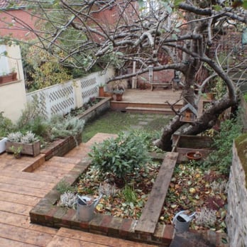 Aquaflora Landscapes - This rectolinear design garden includes two decks, raised reclaimed brick borders with bench tops, random penant path and a turf - Landscaping Near Me