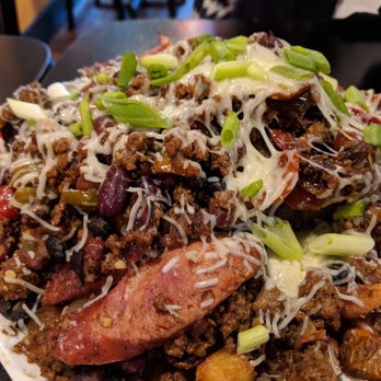 Kuma's Corner - Slayer - 10 oz. burger on a bed of fries, topped with chili, caramalized onions, andouille, cherry peppers, Monterey Jack and scallions - American Near Me - Indianapolis, Indiana
