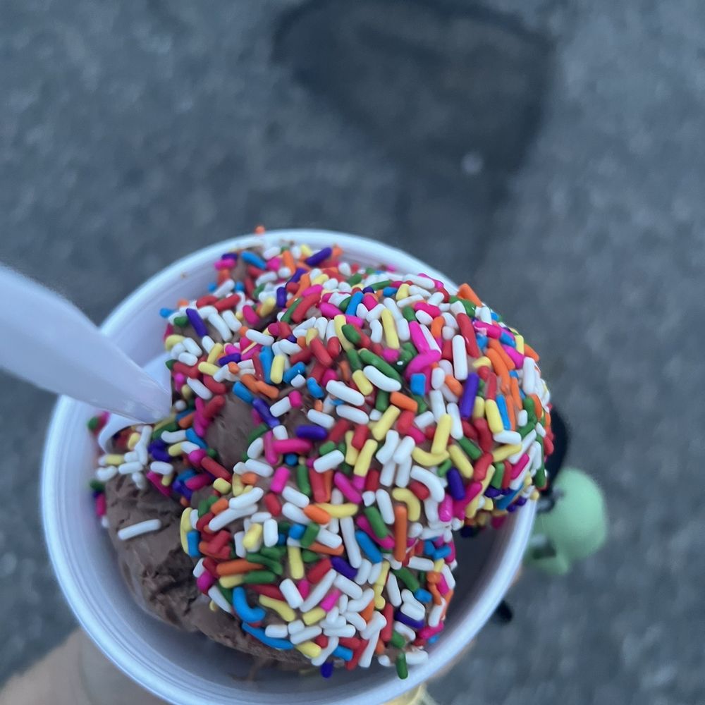 a person holding a cup of ice cream with sprinkles a person holding a cup of ice cream with sprinkles
