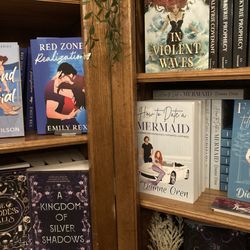 Folklore Grove Bookstore - Selection of romance novels face out on wooden bookshelves.