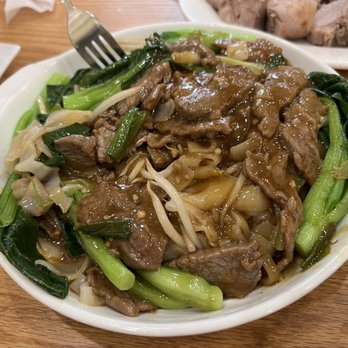 Rongwang Restaurant - Beef chow fun with gravy - Beef chow fun with gravy served in a white bowl, containing beef slices, wide rice noodles, and green vegetables like bok choy. - Noodles Near Me - Flushing, New York
