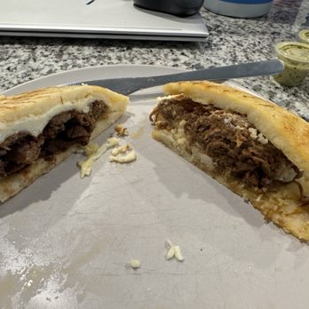 The Arepa Station - This is the carne asada with a grilled cheese slice (left) and shredded beef with shredded white cheese both cut in half to show the inside. - Latin American Near Me - Orlando, Florida