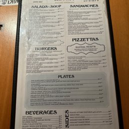 The menu from Cafe Bernardo in Davis, CA displays sections for salads, soups, sandwiches, pizzettas, plates, beverages, and sides. It includes detailed descriptions and prices for items such as mixed greens, Vietnamese sandwiches, grilled salmon, seasonal pizzettas, chicken breast, and various beverages. The menu emphasizes casual dining options with a variety of American and Mediterranean-inspired dishes.