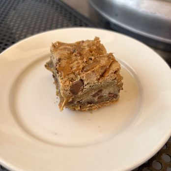 Flying Star Café - Salted Carmel Blondie - A salted caramel blondie with chocolate chips is served on a white plate, featuring caramel drizzle on top. - Bakeries Near Me - Albuquerque, New Mexico