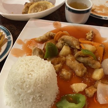 Yen Ching - Sweet and sour pork, potstickers, spring roll and tea. - A plate of sweet and sour pork with rice, accompanied by a spring roll, potstickers, and a cup of tea at a Chinese restaurant. - Chinese Near Me - Ozark, Missouri