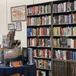 Adventure Bound Books - Bookcases full of non-fiction books with a table of books in the foreground.