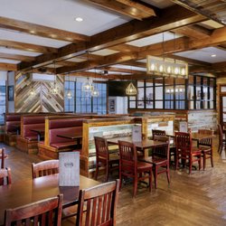 Don’s Seafood - Metairie - The main dining room at our Metairie location, with red leather booths, a colorful reclaimed-wood feature wall, and warm pend...