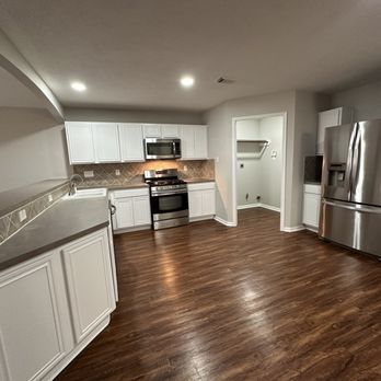 Blue Stone Construction of Texas - a kitchen with white cabinets and wood floors - General Contractors Near Me - Humble, Texas