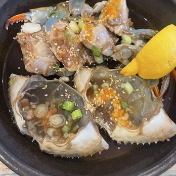 Jang Dok Dae - Raw crabs available Fri to Sun - A dish featuring raw crab pieces garnished with sesame seeds, chopped green onions, and a lemon wedge, served in a black bowl. - Korean Near Me - Flushing, New York