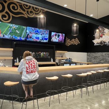 Cravings at Eastvale - a woman watching a football game on tv - Food Court Near Me - Eastvale, California Cravings at Eastvale - a woman watching a football game on tv - Food Court Near Me - Eastvale, California