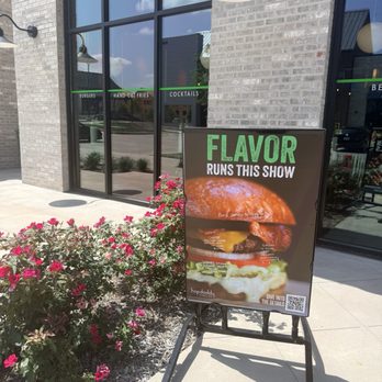 Hopdoddy Burger Bar - Advertisement and pretty flowers in front of building. - Burgers Near Me - McKinney, Texas