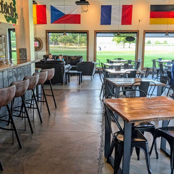 Casper Brewing Company - Inside - A brewery interior features flags on the wall, seating with tables and chairs, and large windows showing a field outside. - Breweries Near Me - Bloomington, Illinois