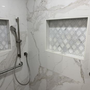 Barrett Tile - A shower area with marble tiles, two recessed niches with patterned tile backs, and stainless steel grab bars for safety. - Tiling Near Me