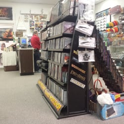 Games Plus - Various merch on the rack and the counter in the background