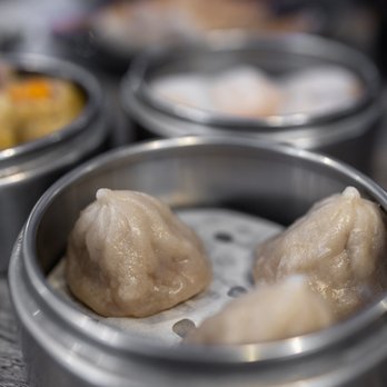 IT DIMSUM - Steamed Pork Dumpling aka XLB ($5) - Three steamed pork dumplings (XLB) are in a metal steamer basket, with other dim sum dishes visible in the background. - Dim Sum Near Me - Albuquerque, New Mexico