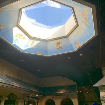 Lino's - The image shows a ceiling with an octagonal skylight, painted to resemble a sky with cherubs and clouds, in an indoor setting with people gathered below. - Pizza Near Me - Rockford, Illinois