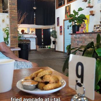 Ital Garden - Fried avocado on wood grain table with partial interior view - Vegan Near Me - New Orleans, Louisiana Ital Garden - Fried avocado on wood grain table with partial interior view - Vegan Near Me - New Orleans, Louisiana