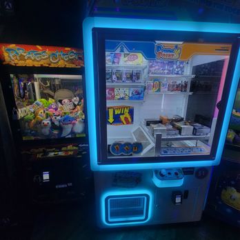 Funtastic Arcade - A claw machine game filled with plush toys of various characters and colors, positioned next to a prize redemption game with toys and boxed items inside. The arcade environment features colorful lighting and gaming machines. - Arcades Near Me - Escondido, California