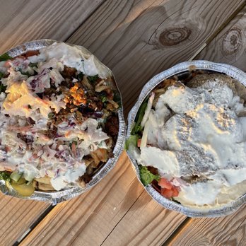 Shawerma Bite - two bowls of food on a wooden table - Two foil containers with Middle Eastern food, including salads, meats, and toppings, placed on a wooden table. - Mediterranean Near Me - Columbus, Ohio