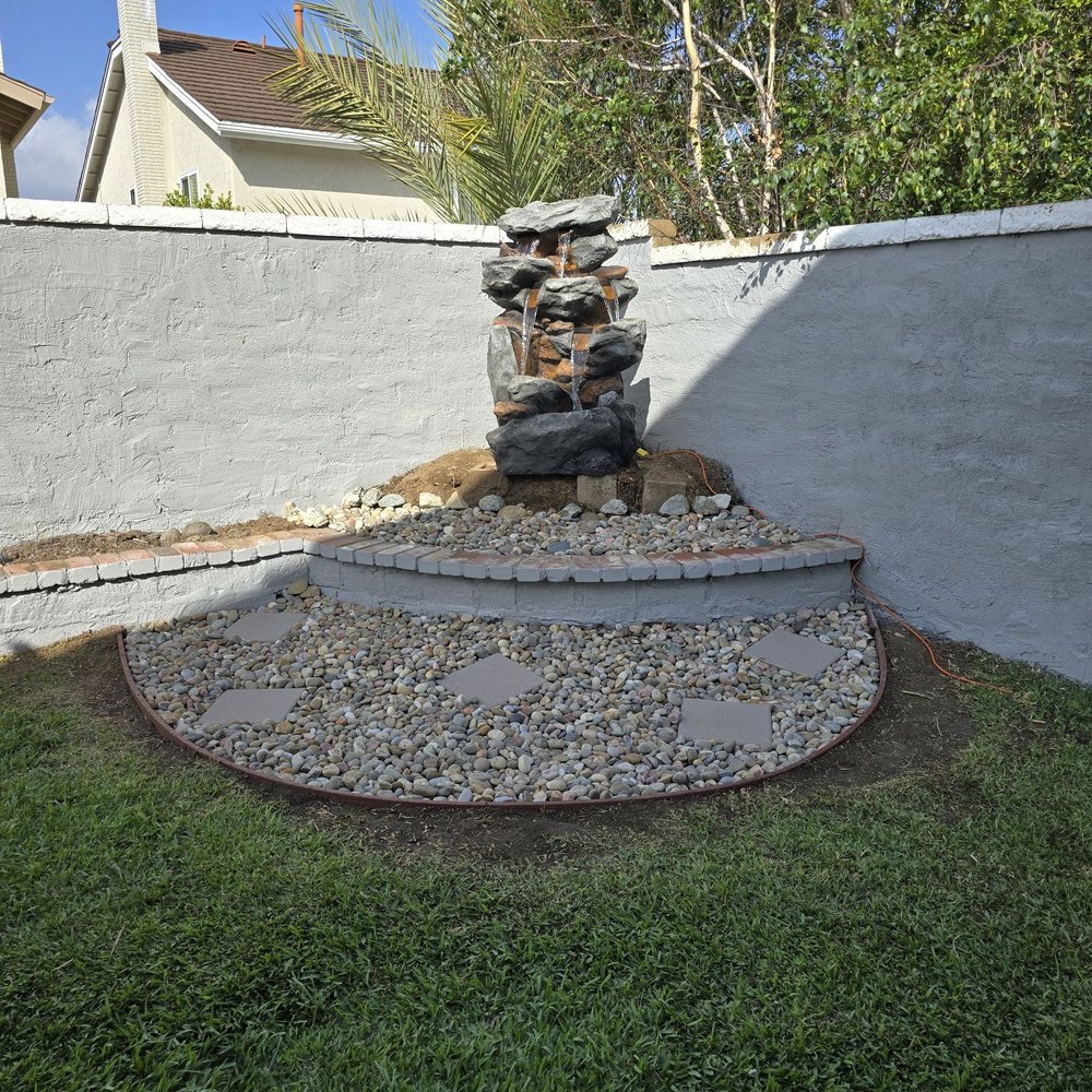 Green Land - Tada!  Fountain installed and working. Mexican pebbles distributed amongst the 2 levels. Pavers set down for plant placement. - Landscaping Near Me