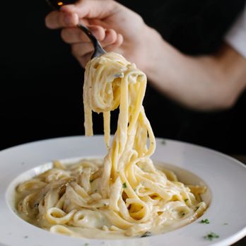 Vendetti's - a person holding a fork over a plate of pasta - Pizza Near Me - Cumming, Georgia