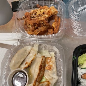 Mirakuya - Brooklyn - Fried Calamari 6 Pieces Gyoza - Fried calamari and gyoza are presented in clear plastic takeout containers, accompanied by soy sauce, on a table with various items. - Japanese Near Me - Brooklyn, New York