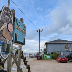 Pelican Pub - Outside. Street sign and gravel parking lot.