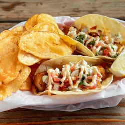 Captain’s Galley - Fish tacos with cabbage, tomatoes, and sauce served with potato chips and a lemon wedge from Captain's Galley