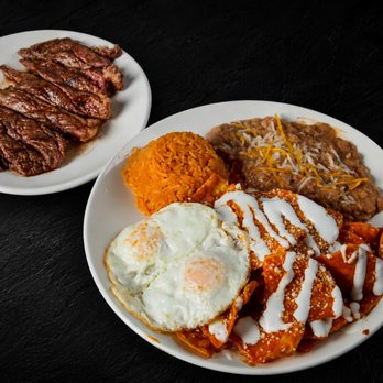 Fuego Cravings - Crispy tortilla chips in red or green sauce, topped with cotija, beans, sour cream, onion, cilantro & eggs. Pictured extra steak on the side - Mexican Near Me - Upland, California Fuego Cravings - Crispy tortilla chips in red or green sauce, topped with cotija, beans, sour cream, onion, cilantro & eggs. Pictured extra steak on the side - Mexican Near Me - Upland, California