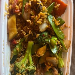 Mixed Vegetable and pork fried rice with king pao sauce - A takeout container holds vegetable fried rice with broccoli, snap peas, zucchini, carrots, and other vegetables, topped with sauce.