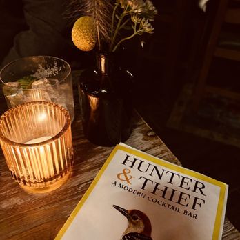 Hunter & Thief - a glass of water and a book on a table - Cocktail Bars Near Me - Lindenhurst, New York