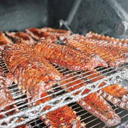 The Fishin' Pig - Farmville - Half racks of delicious smoked baby back ribs glistening on a smoker.