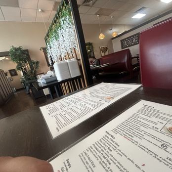 Thai Drift - Inside a Thai restaurant, menus are placed on a dark table with booths and hanging pendant lights in the background. - Thai Near Me - Orem, Utah