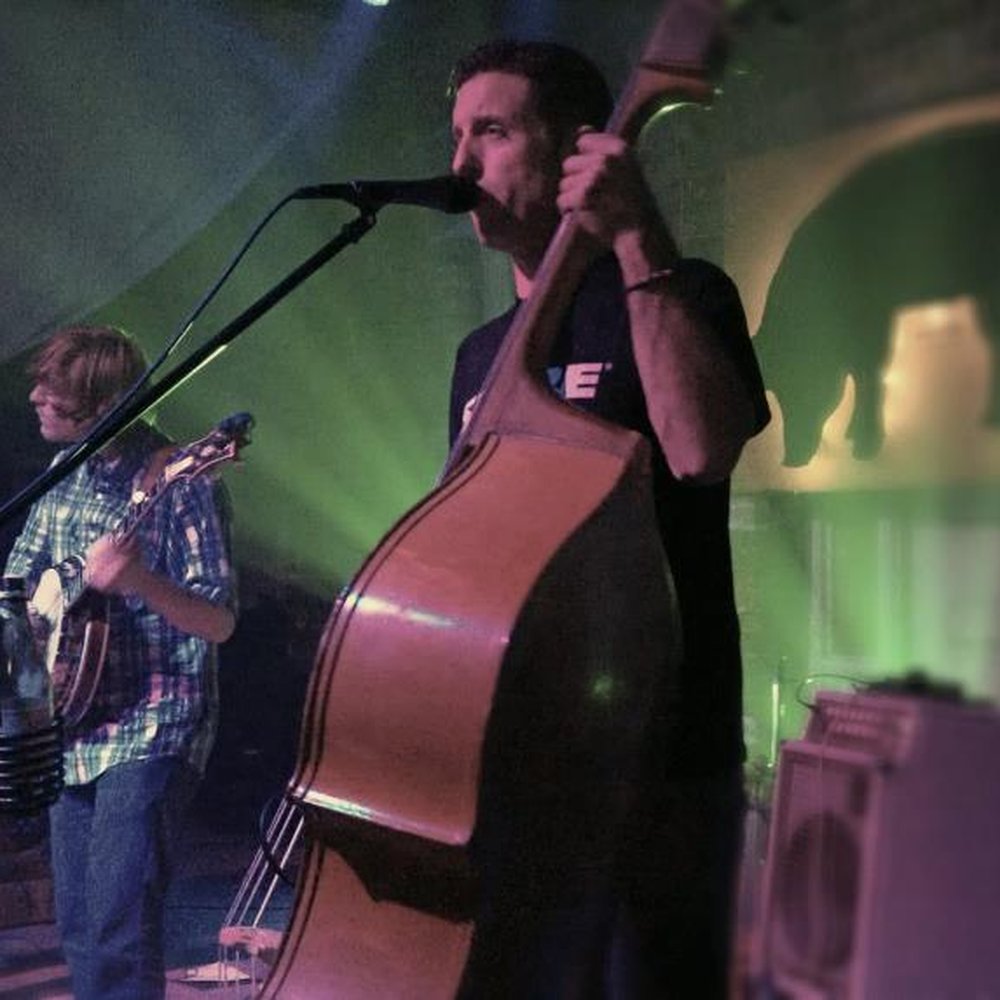 The Elbow - a man playing a cello and singing into a microphone - Bars Near Me - Jacksonville, Florida