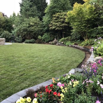 Herick's Landscaping - a garden with flowers in the foreground - Landscaping Near Me Herick's Landscaping - a garden with flowers in the foreground - Landscaping Near Me