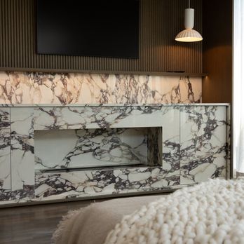 Arete Renovators - A bedroom remodel with a luxurious marble fireplace and reeded wood feature. - General Contractors Near Me - Chicago, Illinois