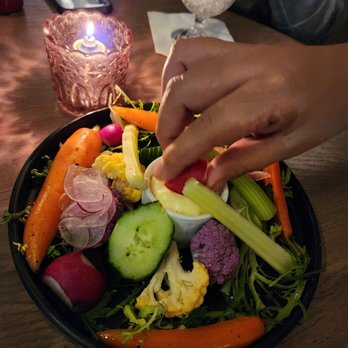 ALMA - a plate of vegetables and a person dipping something into a bowl - Bars Near Me - Chicago, Illinois