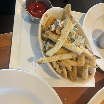 Scratch - Truffle fries - A bowl of French fries garnished with herbs, accompanied by a small cup of ketchup, placed on a white tray. - New American Near Me - Mountain View, California