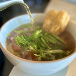 Hanoi Pho: a twist on the traditional pho with sliced ribeye, scallions, thai chili and a fried doughnut. The broth is spicy and delicious!