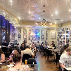 Pizzeria Ludica - Patrons playing board games, eating pizza. See the shelves...those are all the board game options to choose from
