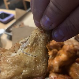 a hand holding a piece of fried buffalo wings a hand holding a piece of fried buffalo wings