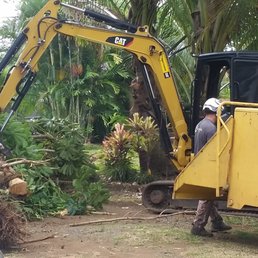 Skillfully wielding the backhoe to make lighter work for his crew, Orrin gingerly lifts the heavy trunks, putting them in the chipper. Skillfully wielding the backhoe to make lighter work for his crew, Orrin gingerly lifts the heavy trunks, putting them in the chipper.