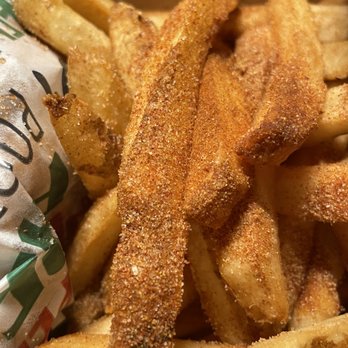 Peri Peri Original - Peri Peri Fries - A close-up image of French fries with a cinnamon sugar coating, displaying a crispy texture and golden-brown color. The fries are piled together, with some wrapped in branded paper, indicating a fast-food or casual dining environment. The seasoning appears evenly distributed, highlighting the sweet and savory flavor combination. - Chicken Shop Near Me - Laurel, Maryland