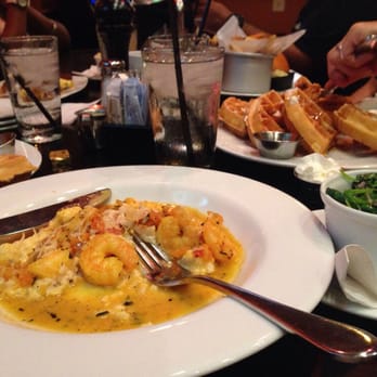 Ben's Next Door - Half eaten shrimp and grits. Waffles in the background, along with a side of spinach. - Bars Near Me - Washington, DC, District of Columbia