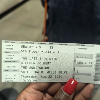 Auditorium Theatre - Saw Stephen Colbert - The image shows a person with red-painted nails holding a ticket for a Stephen Colbert show at the Auditorium Theatre in Chicago. The ticket indicates the event is on August 22, 2024, at 10:00 PM, on the 6th floor, aisle 3, seat 15. The ticket includes details such as the event code, section, row, and seat number, and mentions the show is at the Auditorium Theatre located at 50 E. Ida B. Wells Drive. - Performing Arts Near Me - Chicago, Illinois