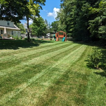 Xperience Lawn Care - a green lawn with a red house in the background - Lawn Services Near Me Xperience Lawn Care - a green lawn with a red house in the background - Lawn Services Near Me