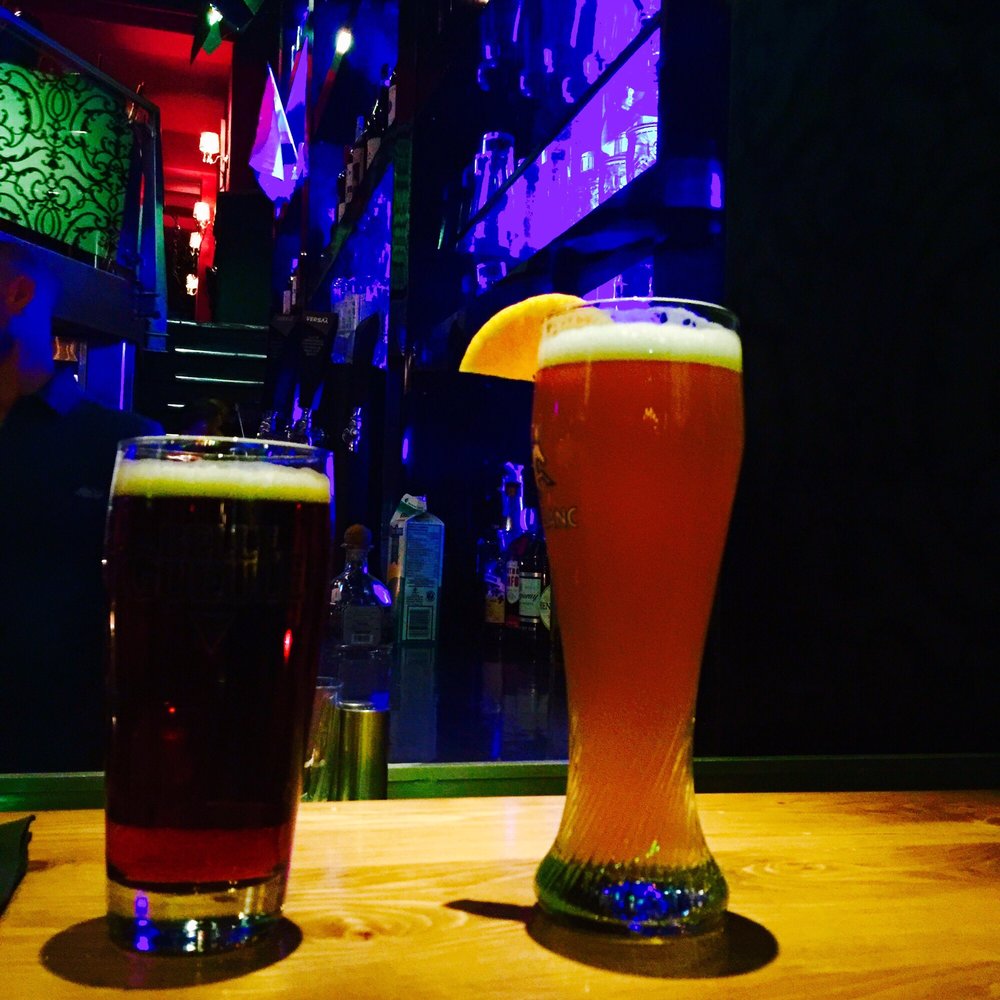 two glasses of beer on a bar counter
