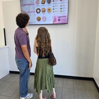 Crumbl - Roanoke - Two customers studying thr menu on the wall. - Bakeries Near Me - Roanoke, Virginia