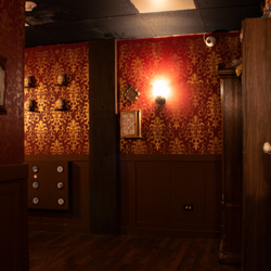 Just Escape Room - Inside The Haunted Doll Shop, vintage dolls line the shelves under dim lighting and ornate wallpaper, setting the perfect eerie tone.